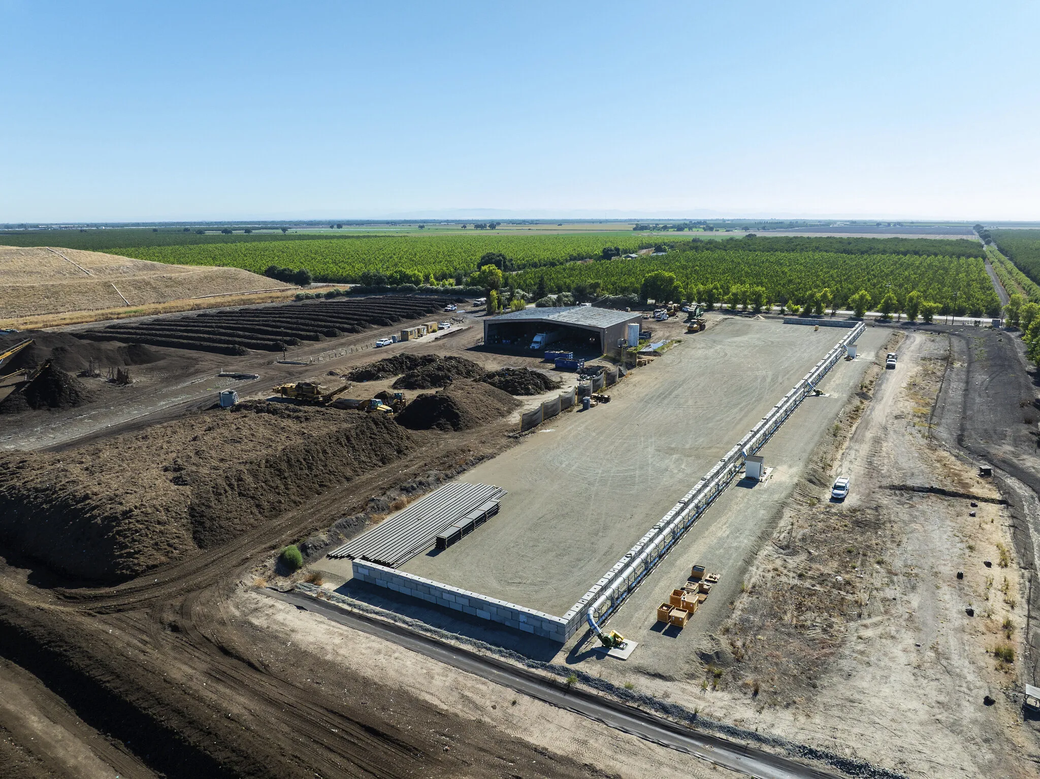 Aerial view of a compost facility with windrows, equipment, and surrounding farmland.