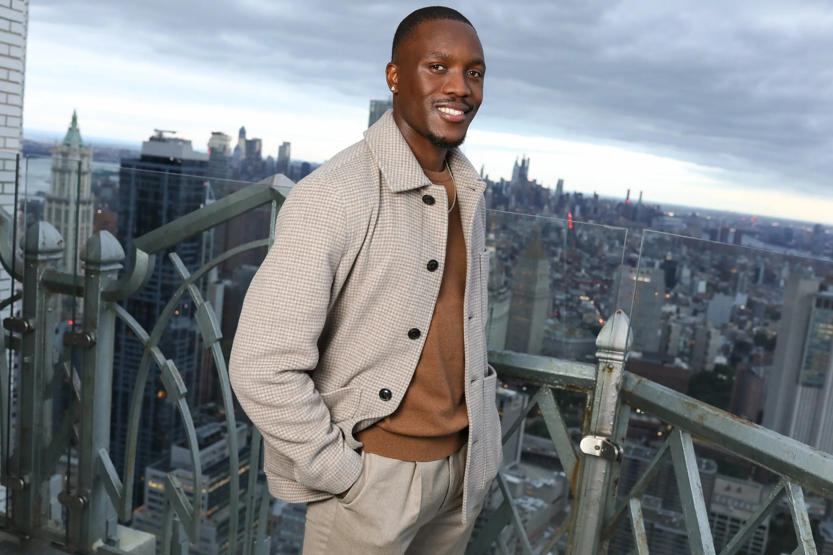 Letsile Tebogo stands on a rooftop balcony overlooking a city skyline.
