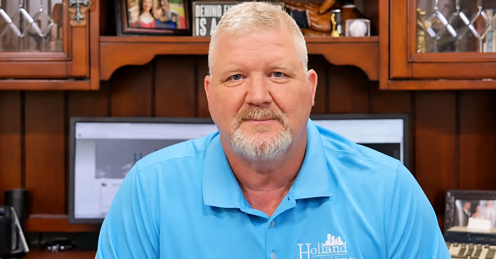 A person in a blue polo shirt sits in an office.