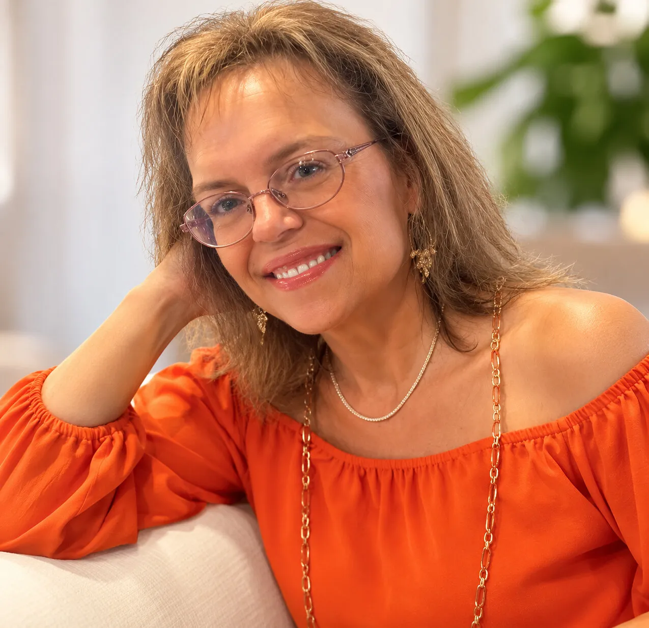 Michaelle Bragassa wearing glasses and an orange off-the-shoulder top.
