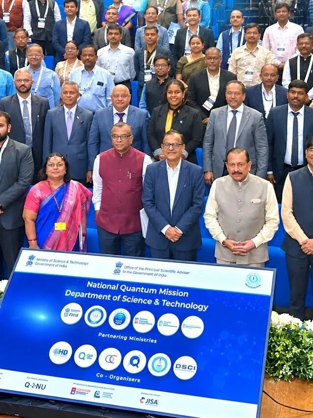Group of attendees standing behind a National Quantum Mission sign at a conference.