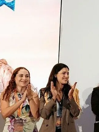 Eight attendees applaud a person holding an award certificate onstage beneath a Los Cabos sign.